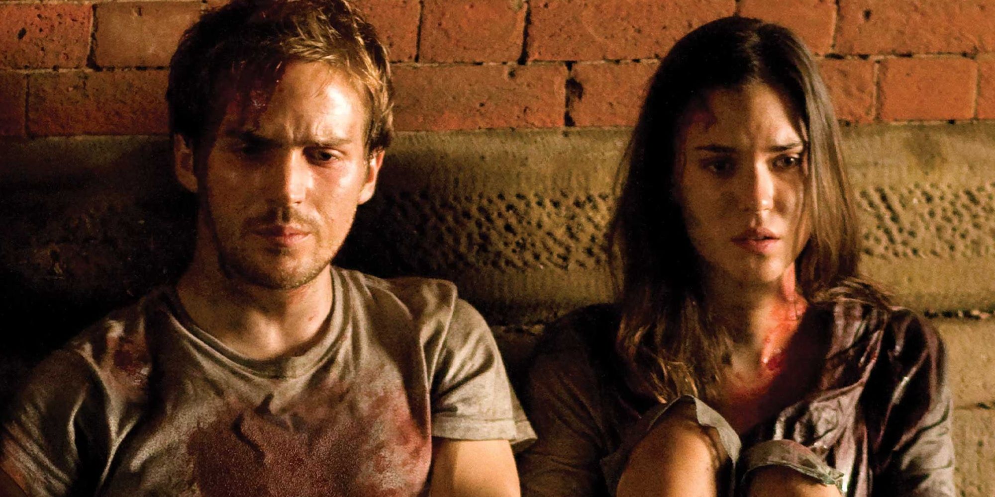 Rob and Beth looking mortified against a brick backdrop in Cloverfield