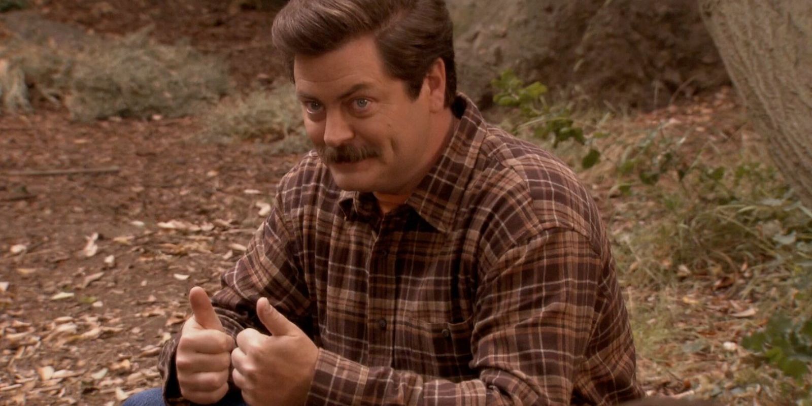 Ron gives two thumbs up while sitting in nature.