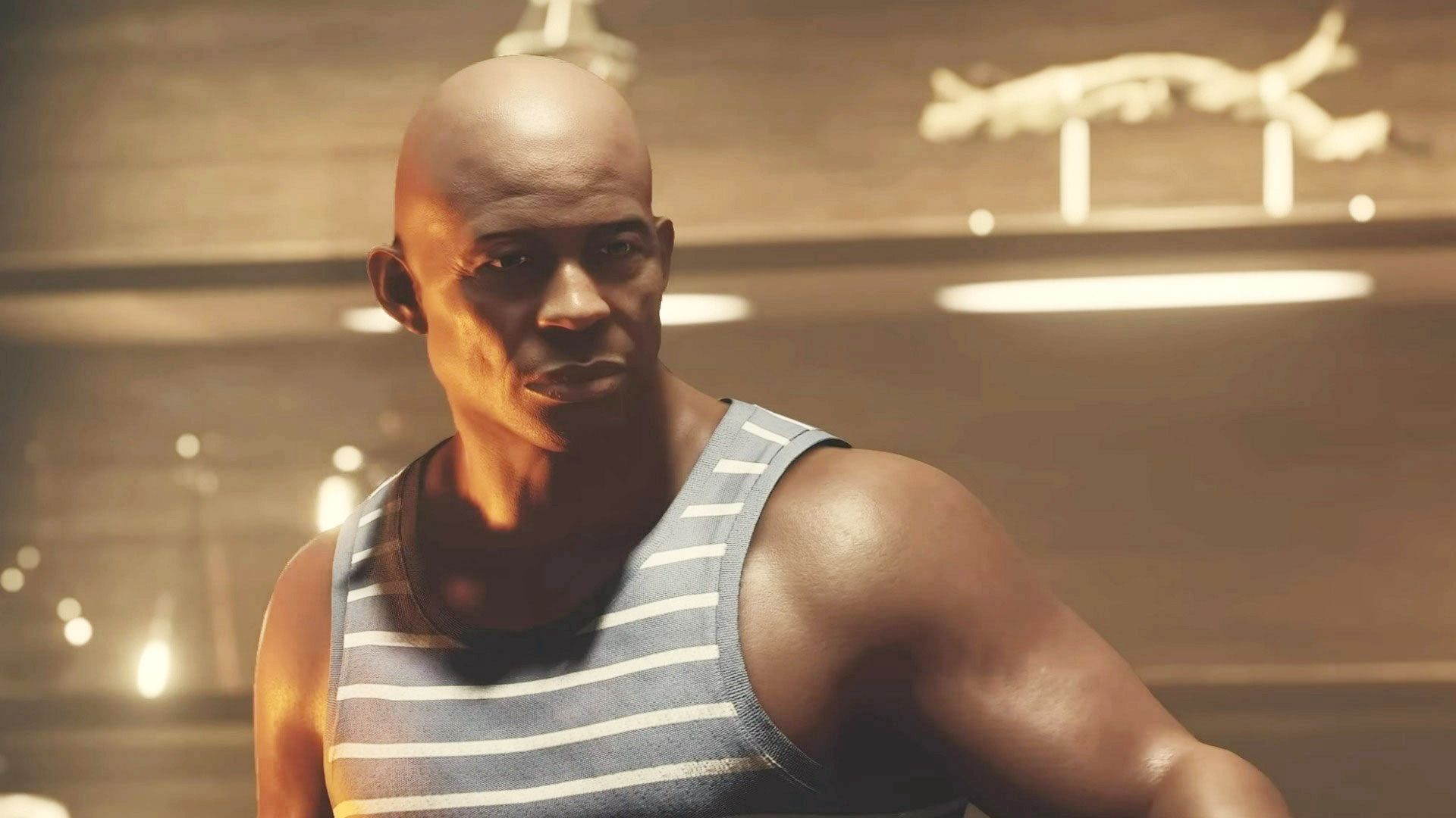 Vladimir Sall, a bald black man in a blue and white striped tank top, stands against a blurry golden background.