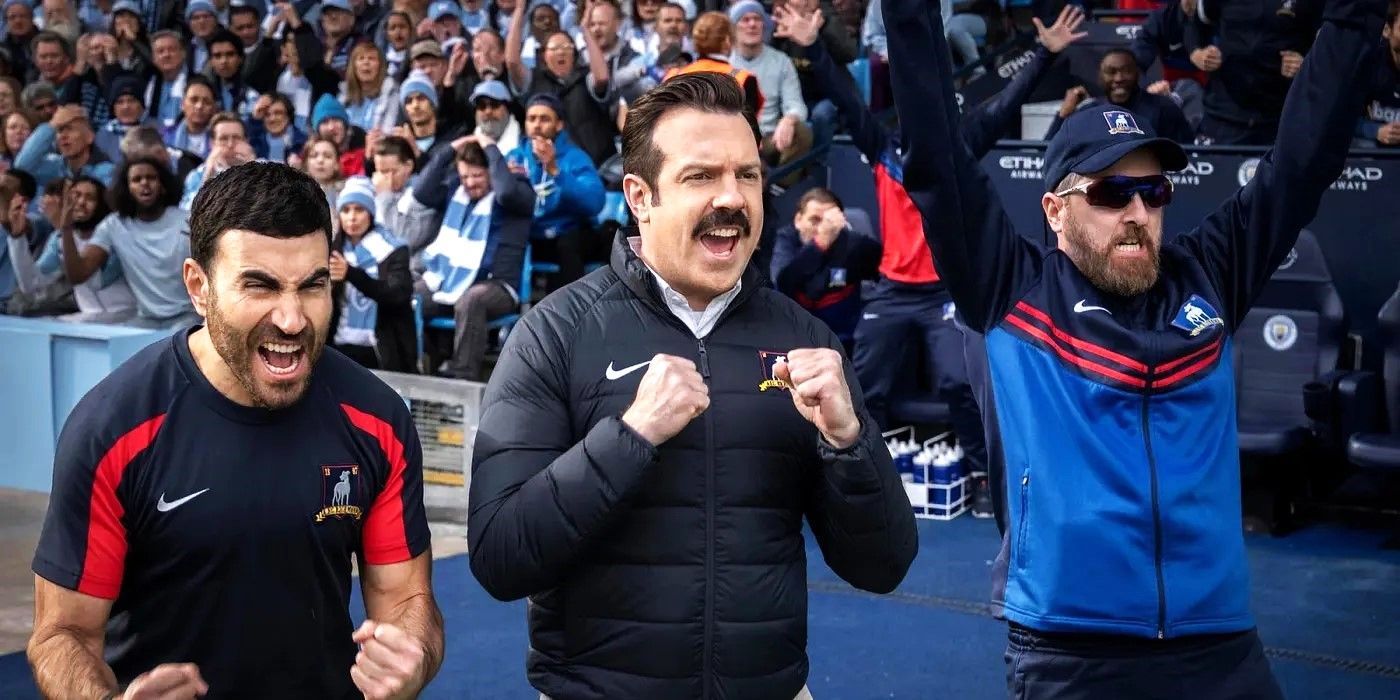 Jason Sudeikis as Ted Lasso Brett Goldstein as Roy Kent and Brendan Hunt as Coach Beard cheering on the pitch in Ted Lasso