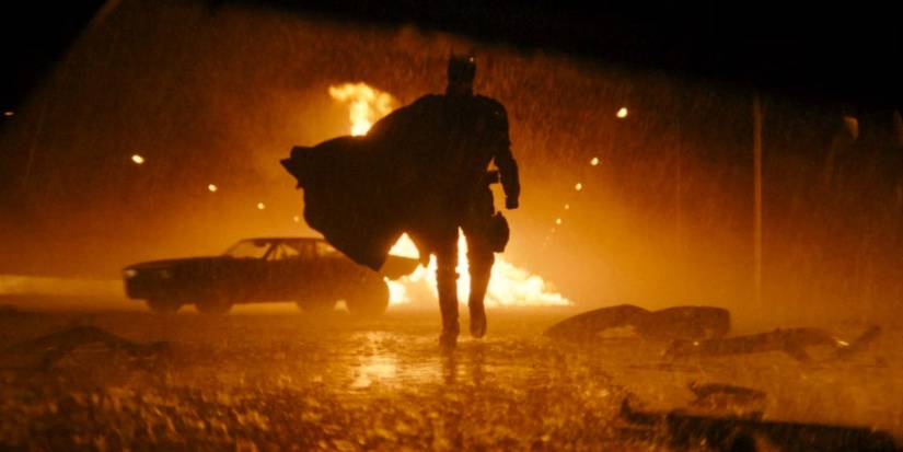 Robert Pattinson as Batman in The Batman walking away from the Batmobile.