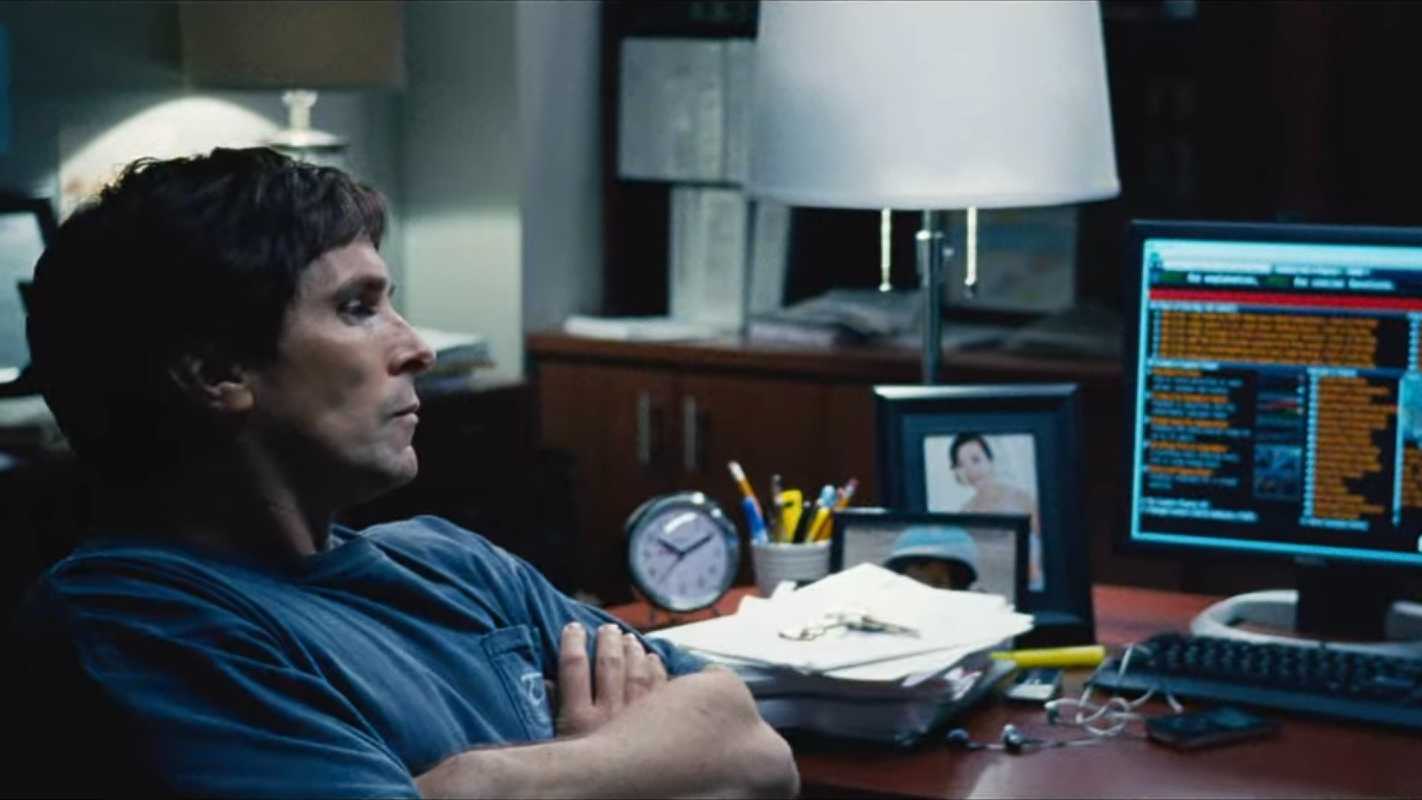 Michael Burry (Christian Bale) looking at computer monitors in The Big Short