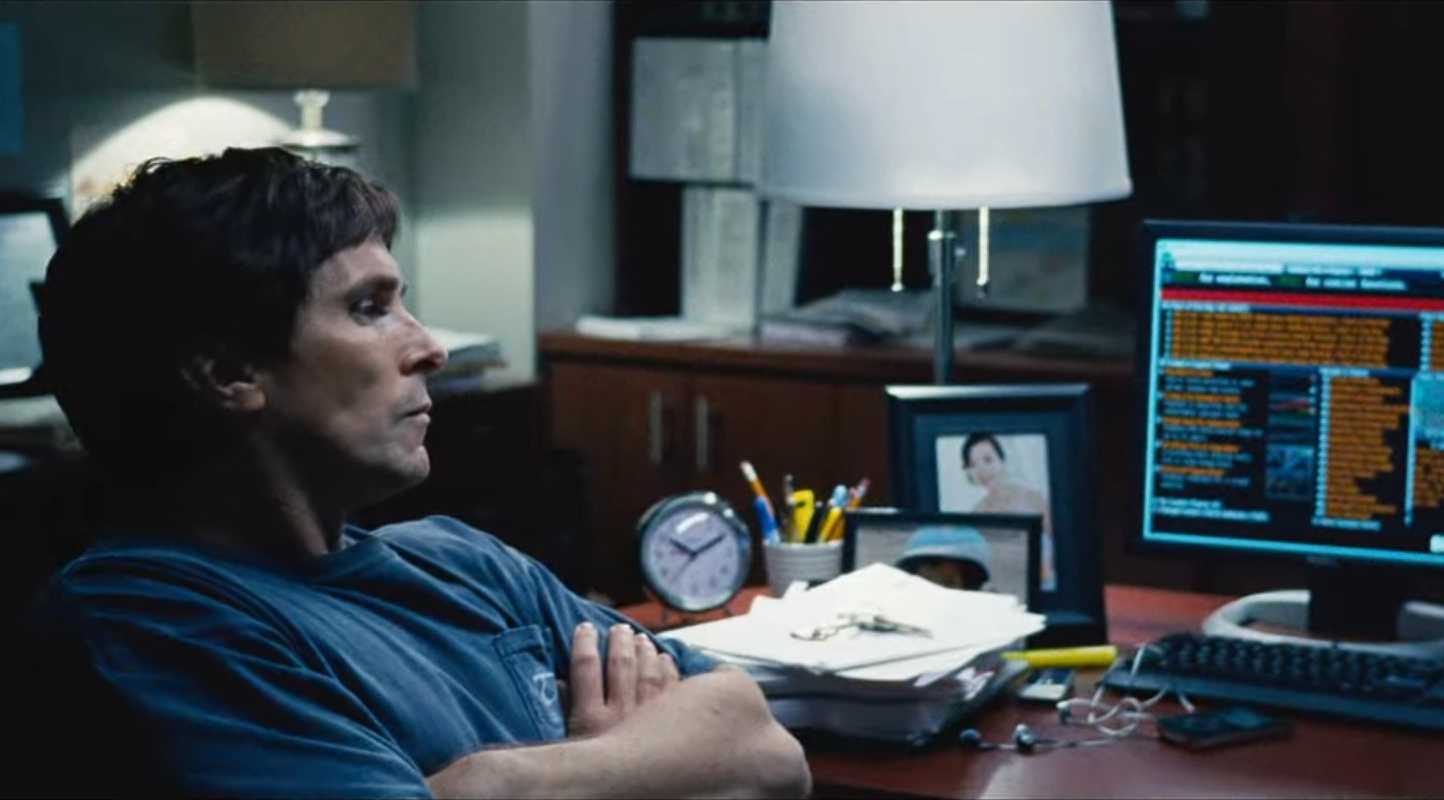 Michael Burry (Christian Bale) looking at computer monitors in The Big Short