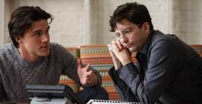 Finn Wittrock as Jamie Shipley and John Magaro as Charlie Geller staring at a phone in The Big Short.