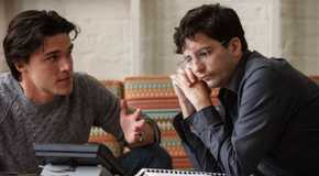 Finn Wittrock as Jamie Shipley and John Magaro as Charlie Geller staring at a phone in The Big Short.