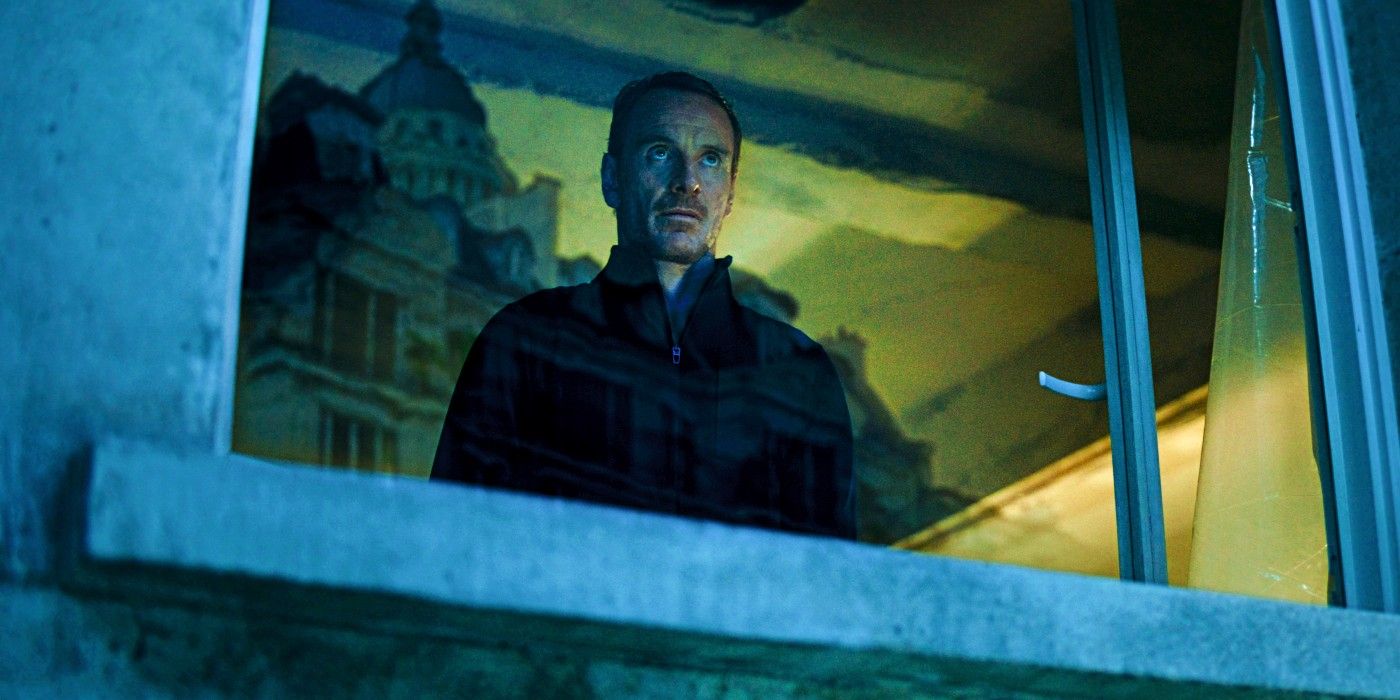Michael Fassbender looks through a window in The Killer
