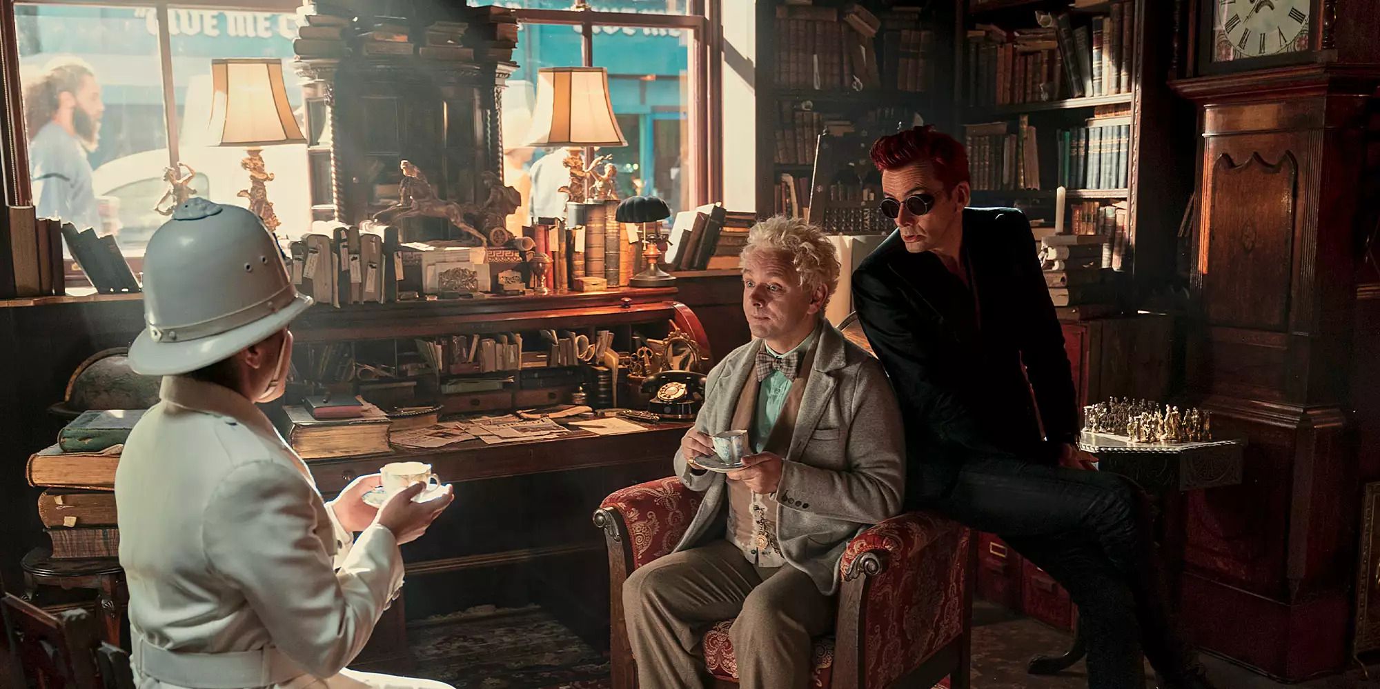 Aziraphale and Crowley talk to Muriel who is dressed as a police officer, in the bookshop