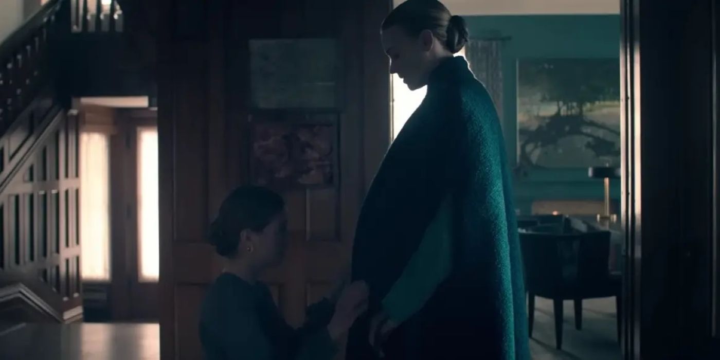 Alanis Wheeler kneeling and praying over Serena’s pregnancy in The Handmaid’s Tale.