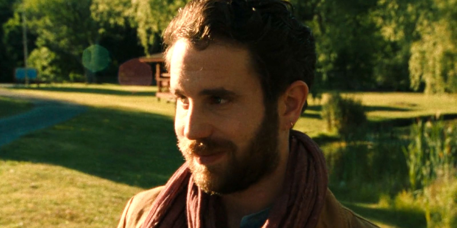 Amos stands outside smiling in the sunlight.