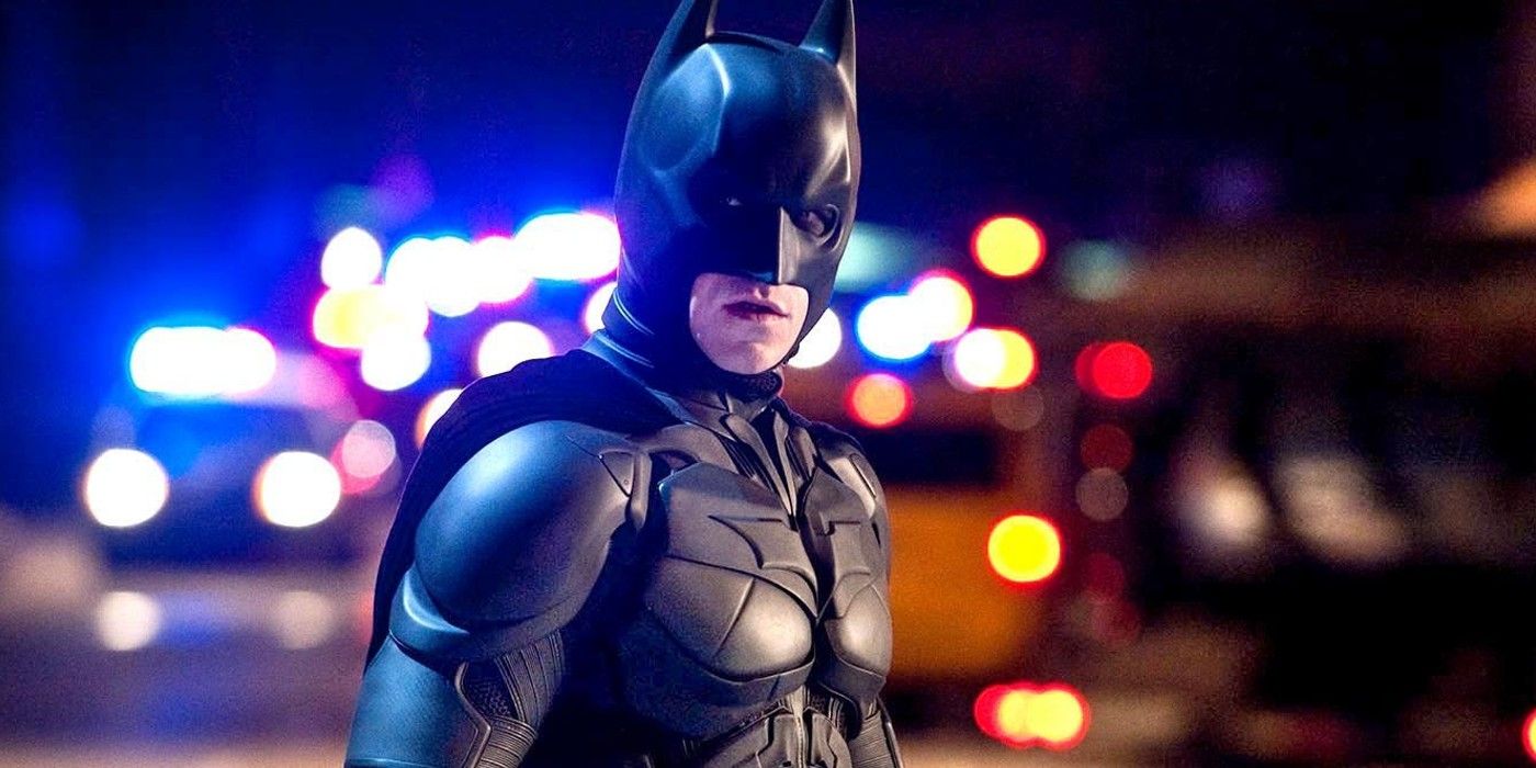 Batman (Christian Bale) stands in front of police lights in The Dark Knight Rises