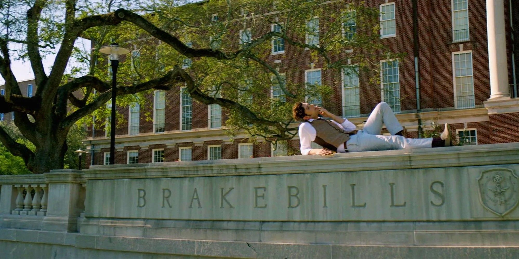   Elliott deita na placa da Universidade Brakebills fumando em The Magicians.