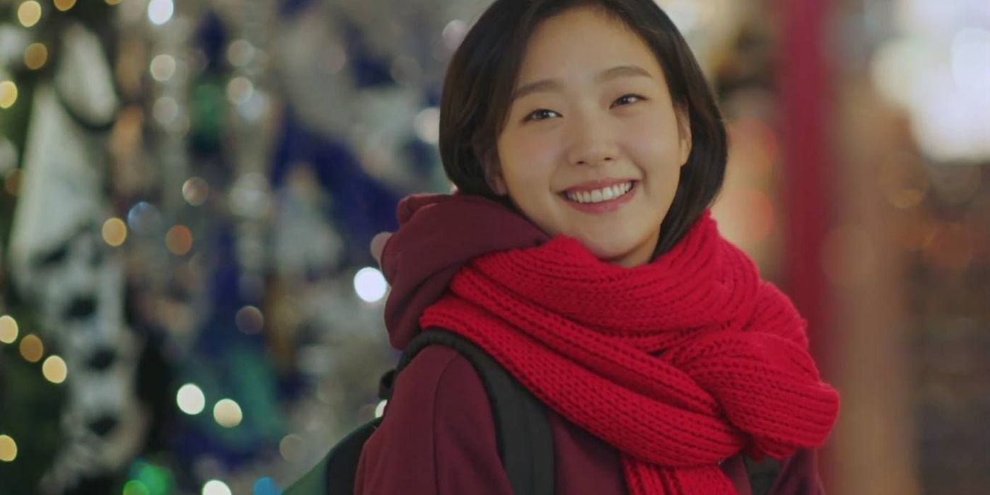 Yeun-Tak smiles while wearing a red scarf.