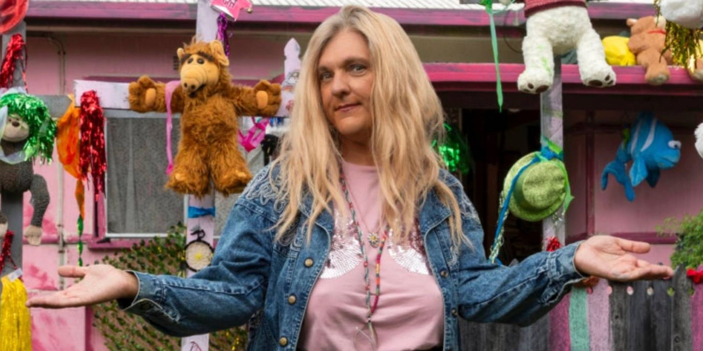 Chris Lilley in a blonde wig and surrounded by stuffed animals in Lunatics