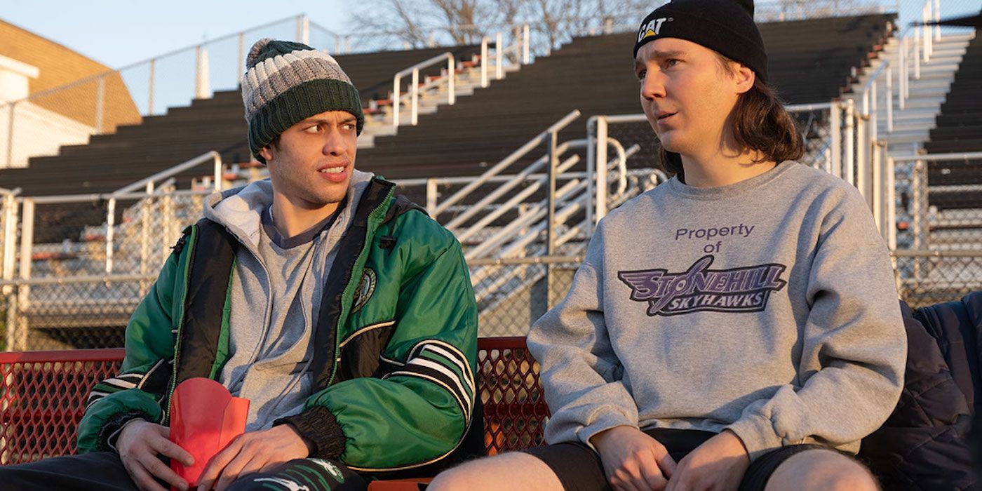 Paul Dano and Pete Davidson sit on a bench in Dumb Money