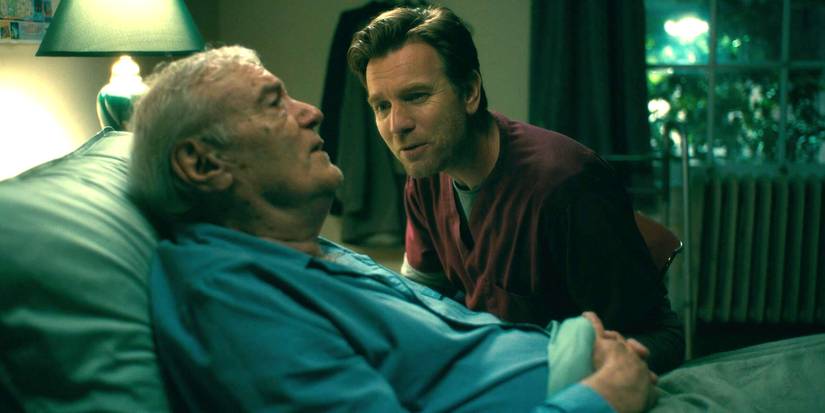 Ewan McGregor as Danny sitting by an old man in bed in Doctor Sleep