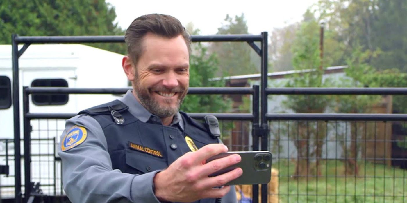Joel McHale as Frank smiles and takes a photo in Animal Control