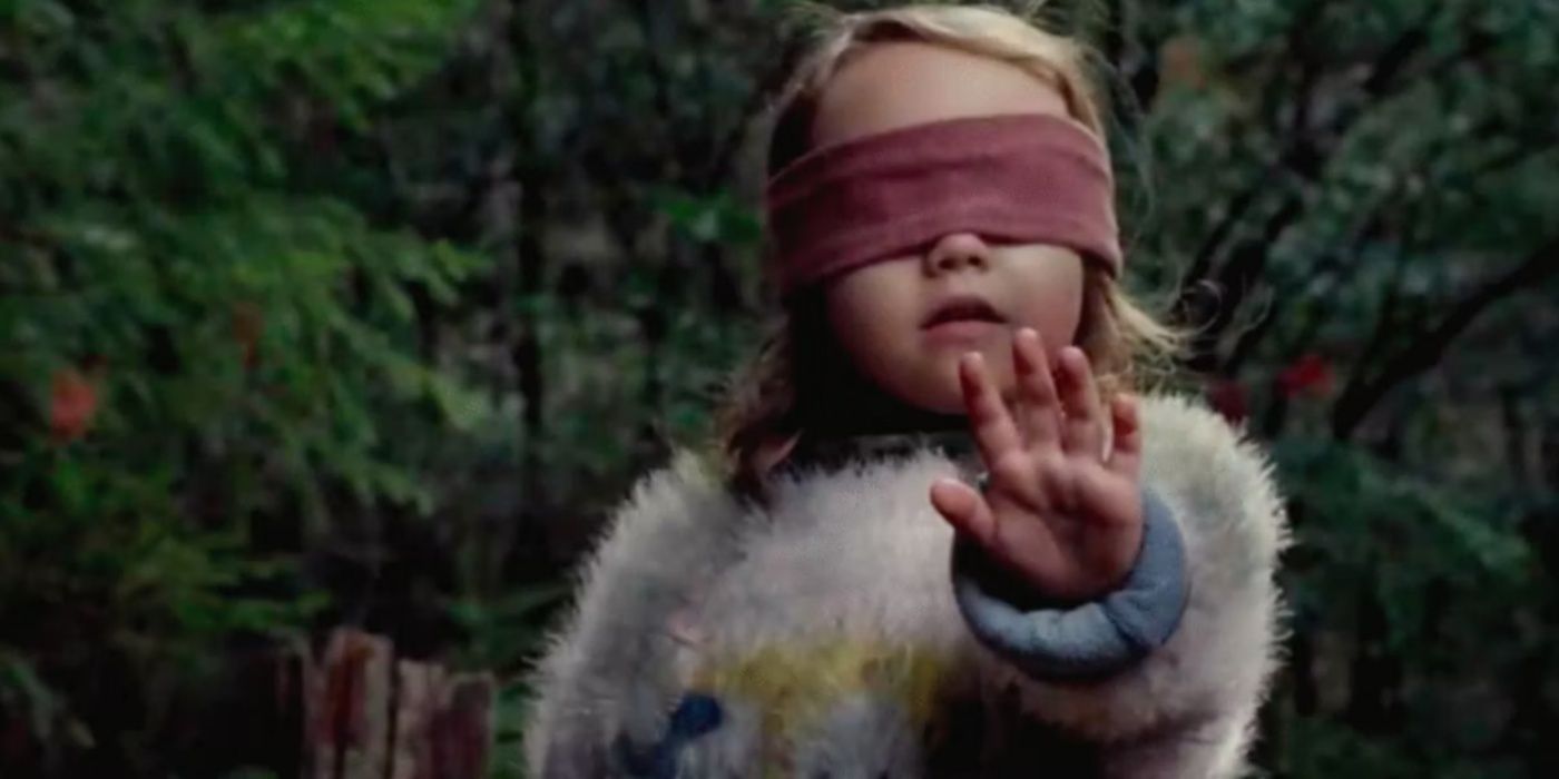 Girl with her hand up towards the creatures in Bird Box