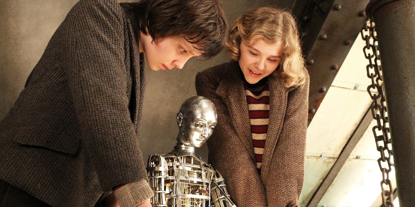 Hugo (Asa Butterfield) e Isabelle (Chloe Grace Moretz) olhando para um homem mecânico no filme Hugo 2011