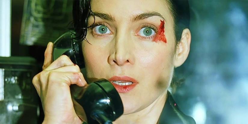 Carrie-Anne Moss as Trinity on the phone with blood on her face in The Matrix. 