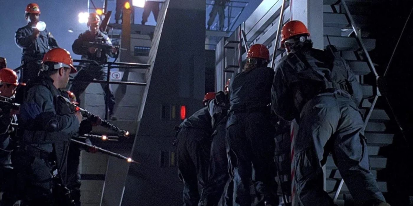 Trabalhadores do lado de fora à noite com armas apontadas para uma jaula em Jurassic Park.