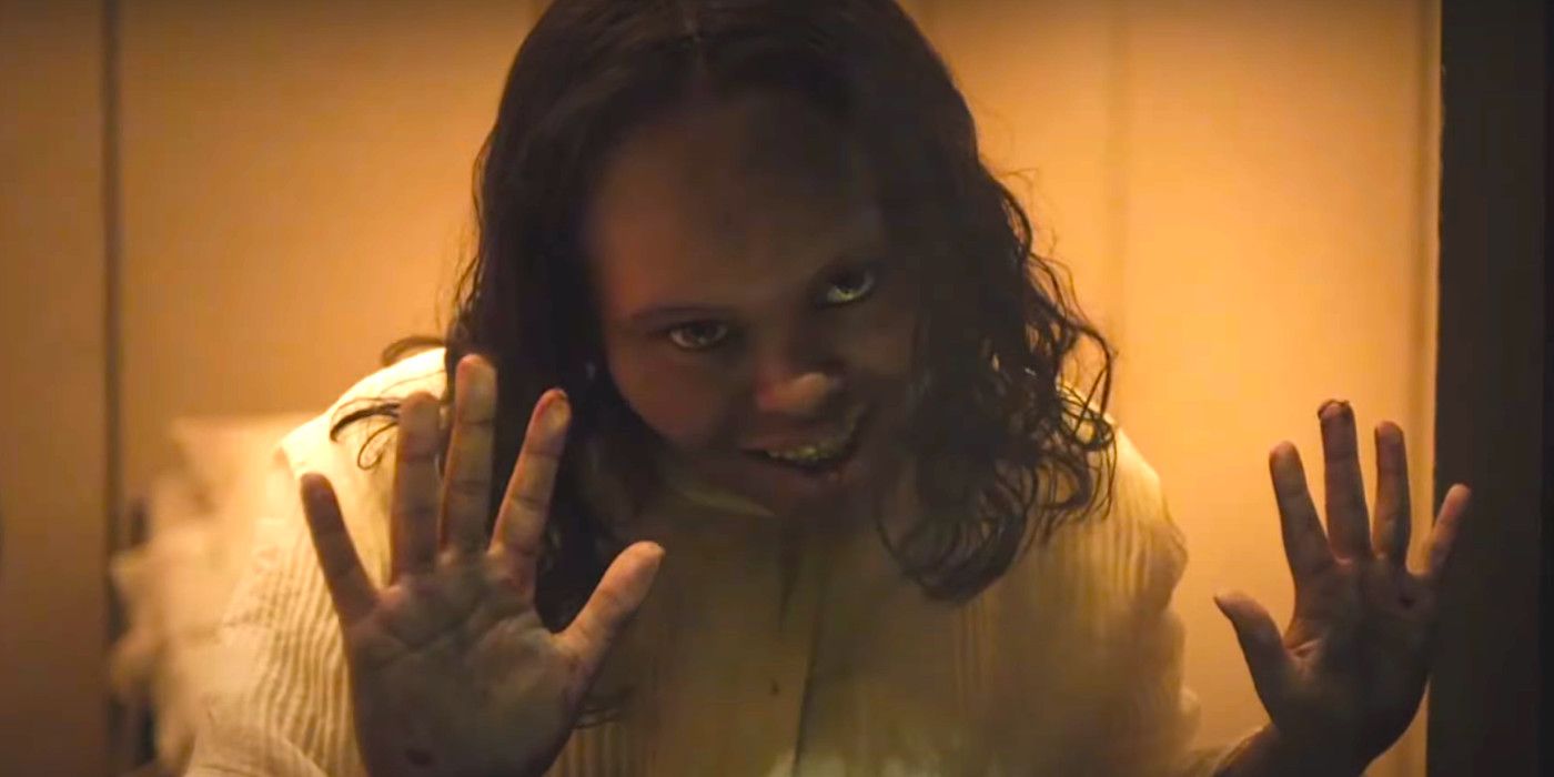 Lidya Jewett smiling creepily and pressing her hands to the glass in The Exorcist Believer