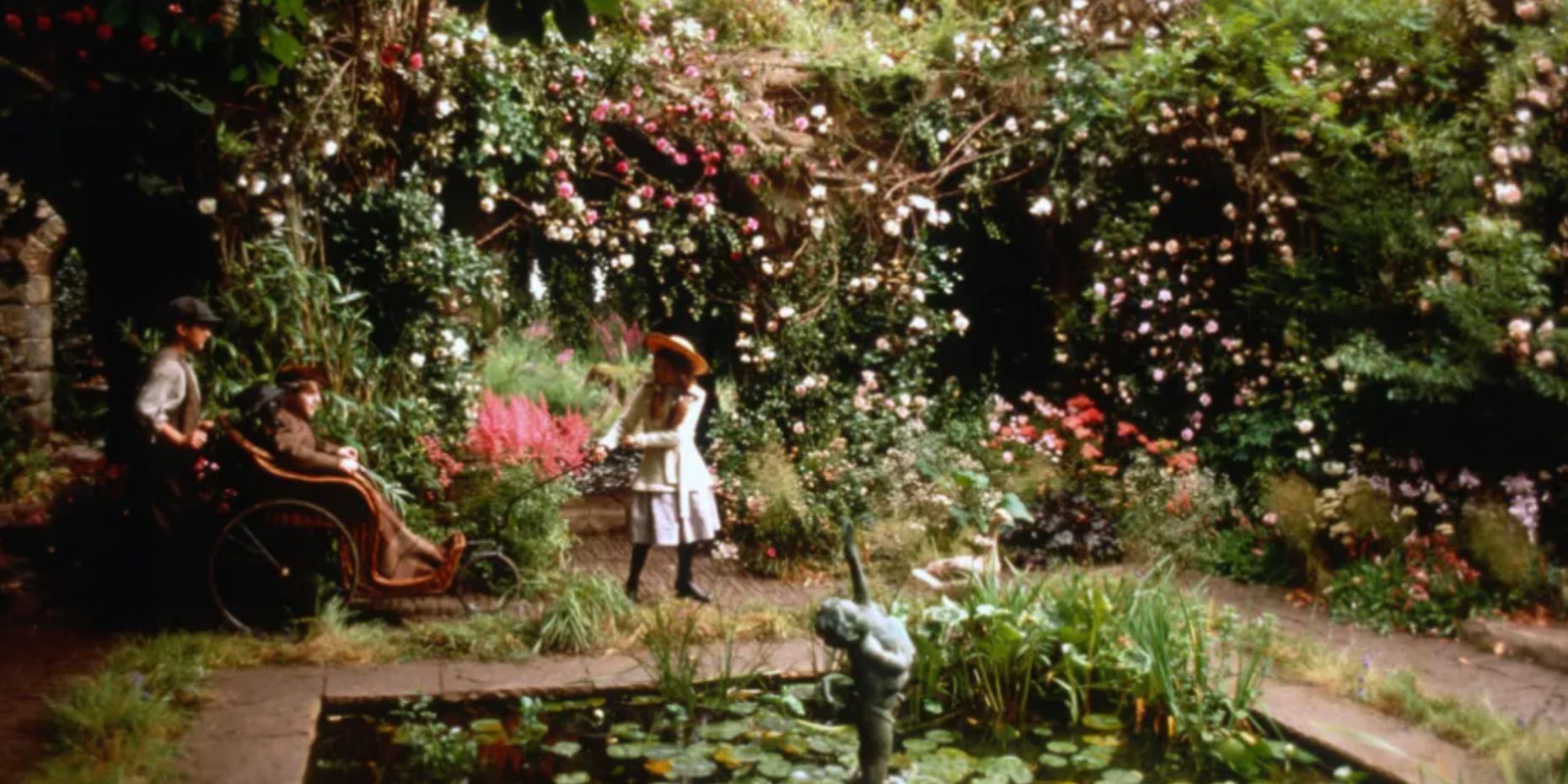 Mary pulls her cousin and his wheelchair into the secret garden while Dickon pushes in The Secret Garden