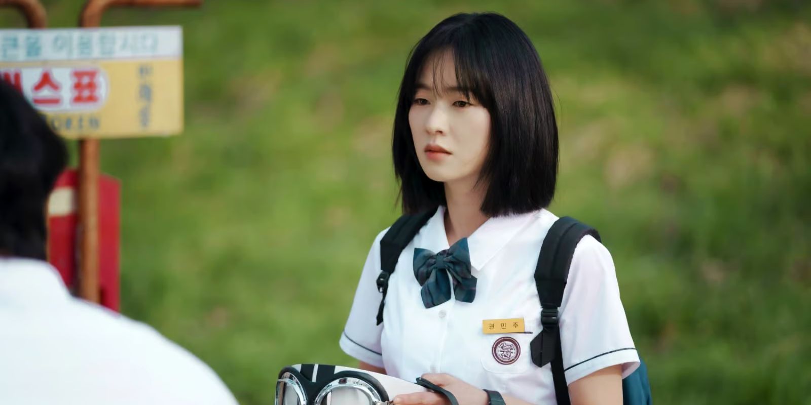 Min-ju holds a bike helmet in her hands while looking at her friend.