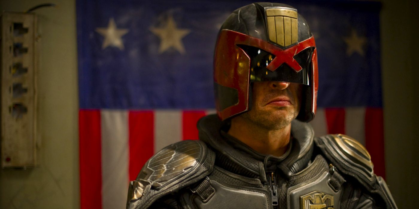 Karl Urban as Judge Dredd standing in front of an American flag in Dredd.