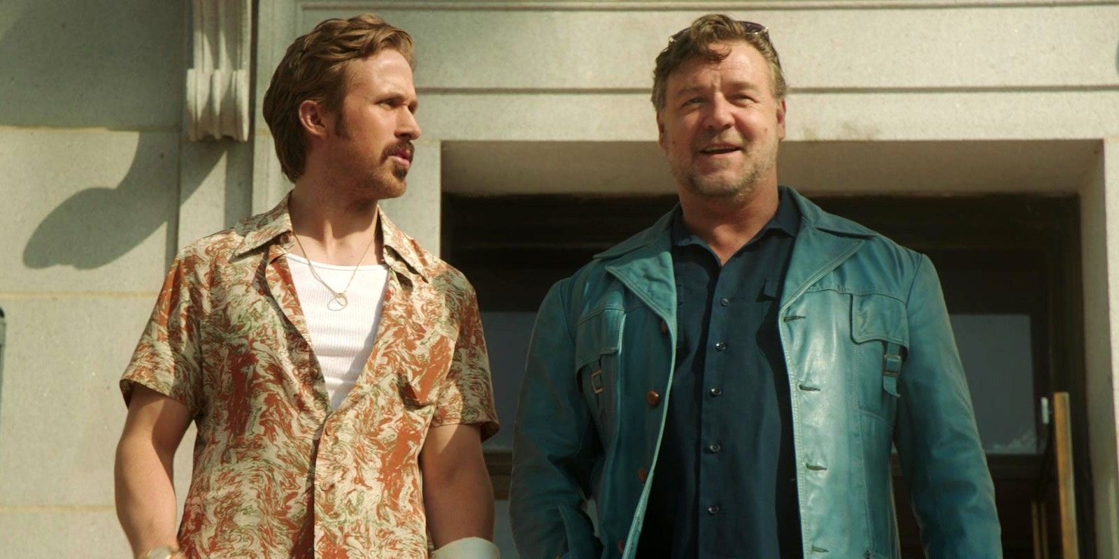 Ryan Gosling olhando para Russell Crowe sorridente enquanto está do lado de fora em The Nice Guys