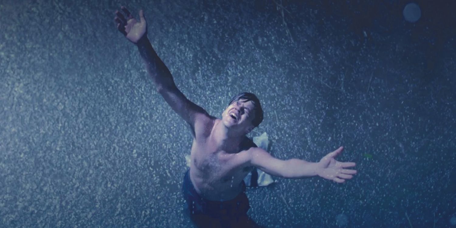 Tim Robbins stands with his arms raised to the sky in the rain in The Shawshank Redemption.