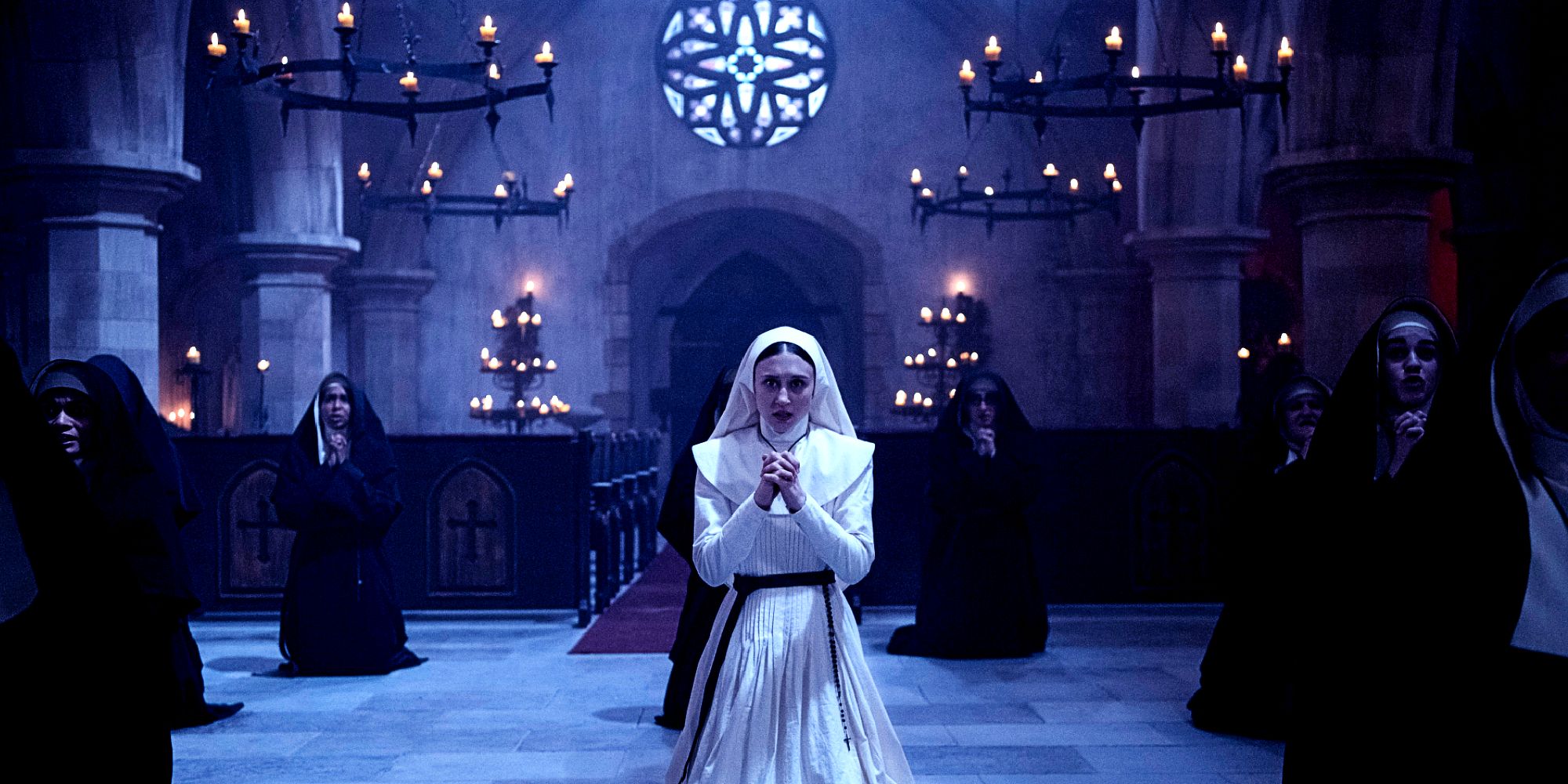 Taissa Farmiga as Sister Irene on her knees praying with other nuns in The Nun