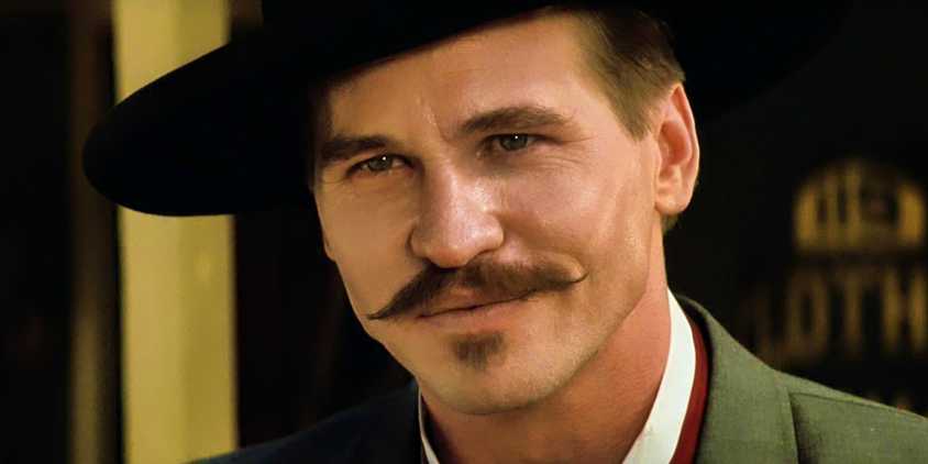 Val Kilmer as Doc Holliday smirking and looking sick in Tombstone 1993
