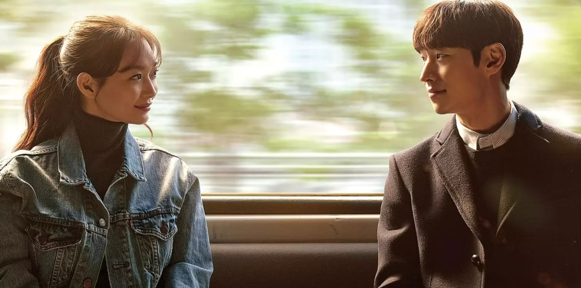A woman and a man smile at one another in front of a window on a subway in the time travel Kdrama Tomorrow With You