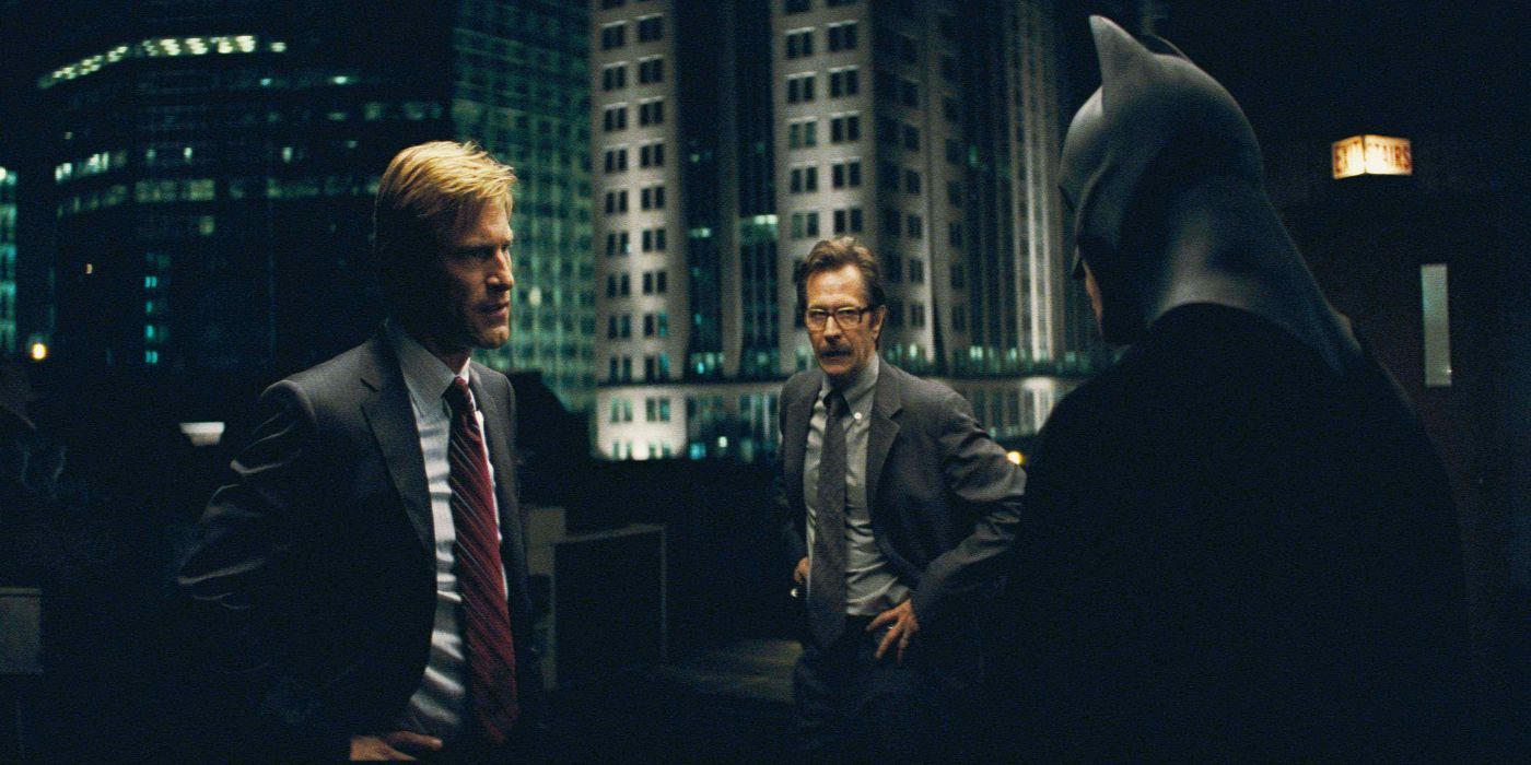 Aaron Eckhart, Christian Bale and Gary Oldman talking on a rooftop in The Dark Knight