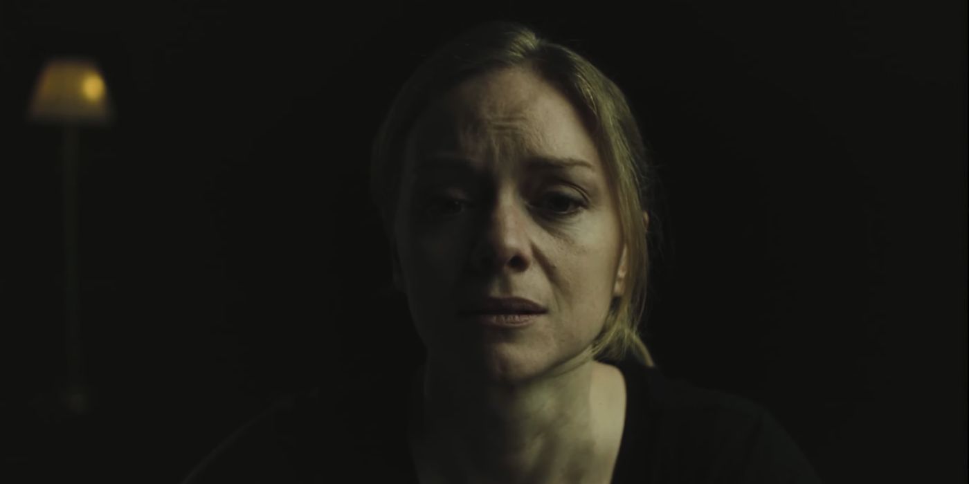 Alice appears overcome by emotion, half her face obscured in darkness in a screenshot from one of Alan Wake 2's live-action cutscenes.