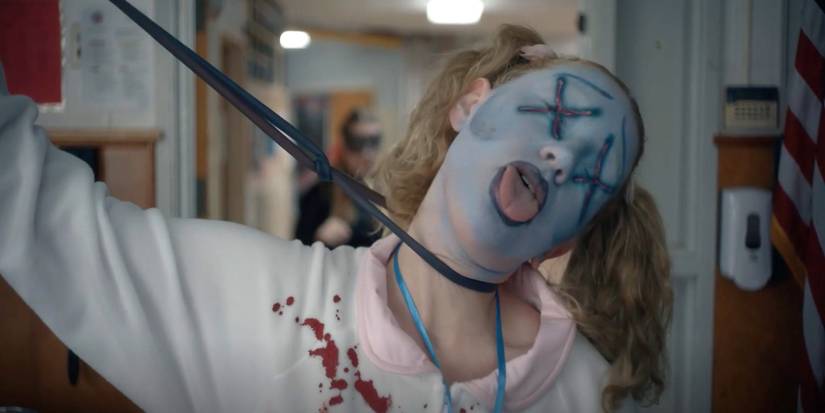 Shelby being chocked by a black rope, blood on her outfit, face painted, in American Horror Sotry