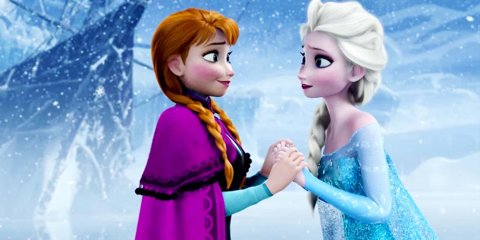 Anna and Elsa hold hands and smile at one another in Frozen