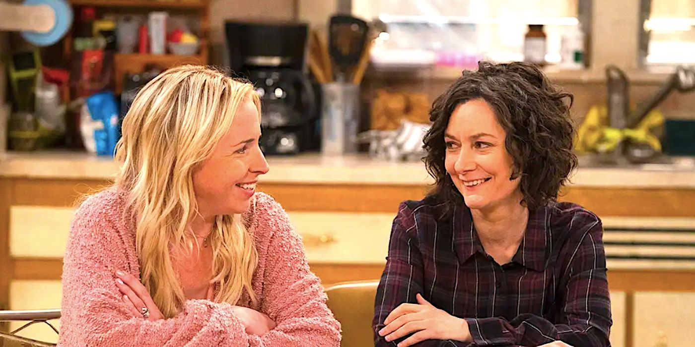 Lecy Goranson's Becky and Sara Gilbert's Darlene sit at the kitchen table laughing in The Conners