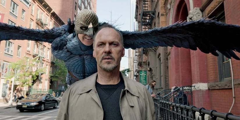 Birdman flies behind Michael Keaton as he walks down the street in Birdman