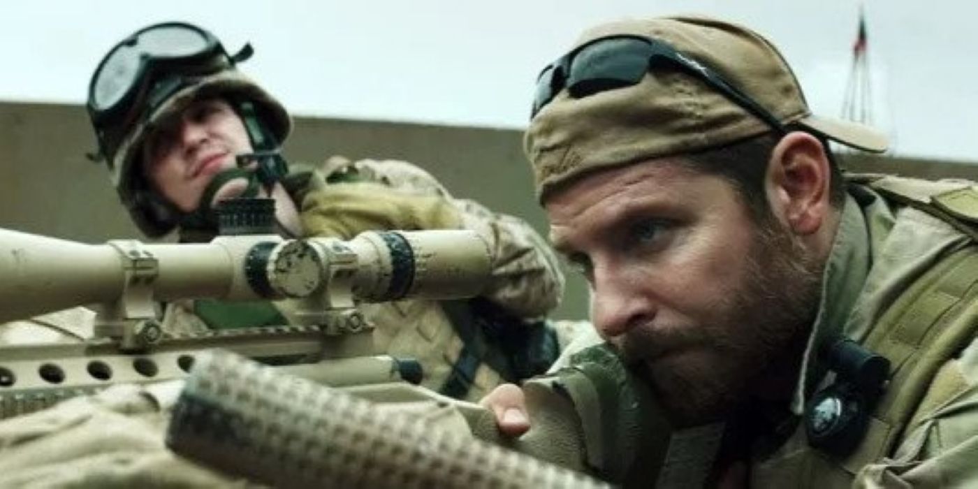 Bradley Cooper as Chris Kyle aiming his rifle next to a spotter in American Sniper.