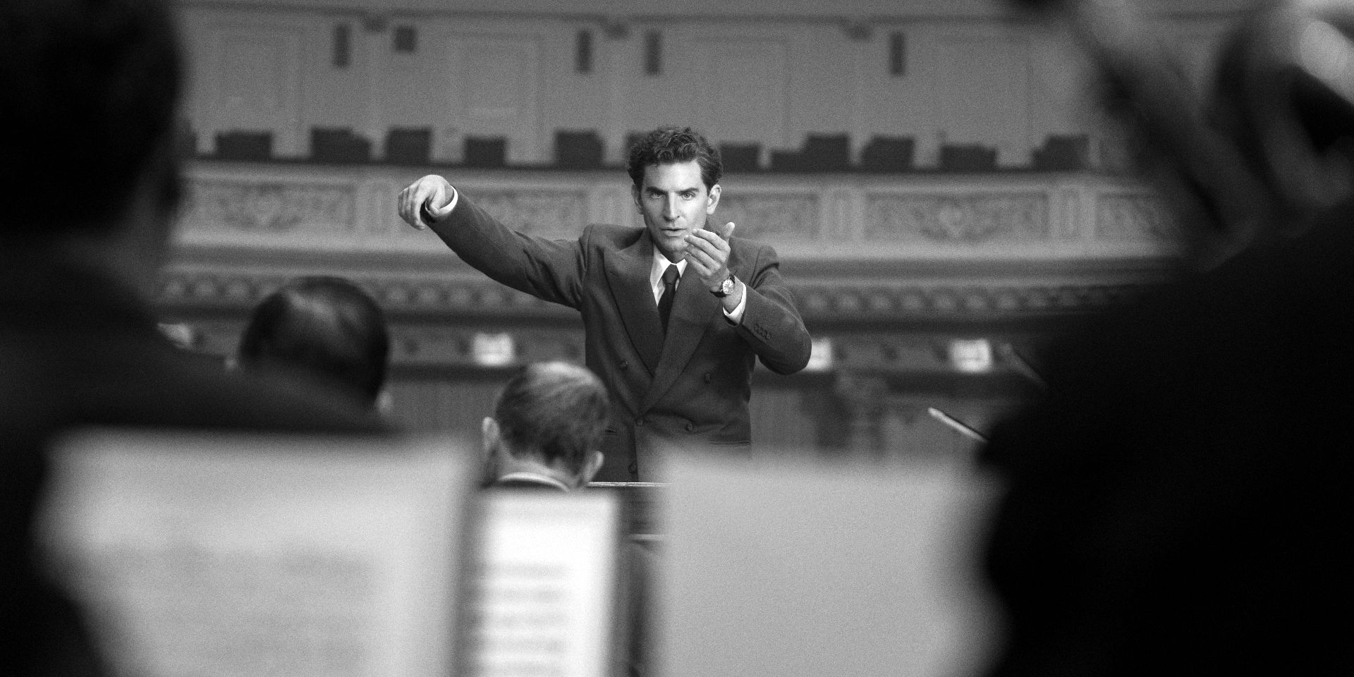 A black-and-white image of Bradley Cooper composing in Maestro