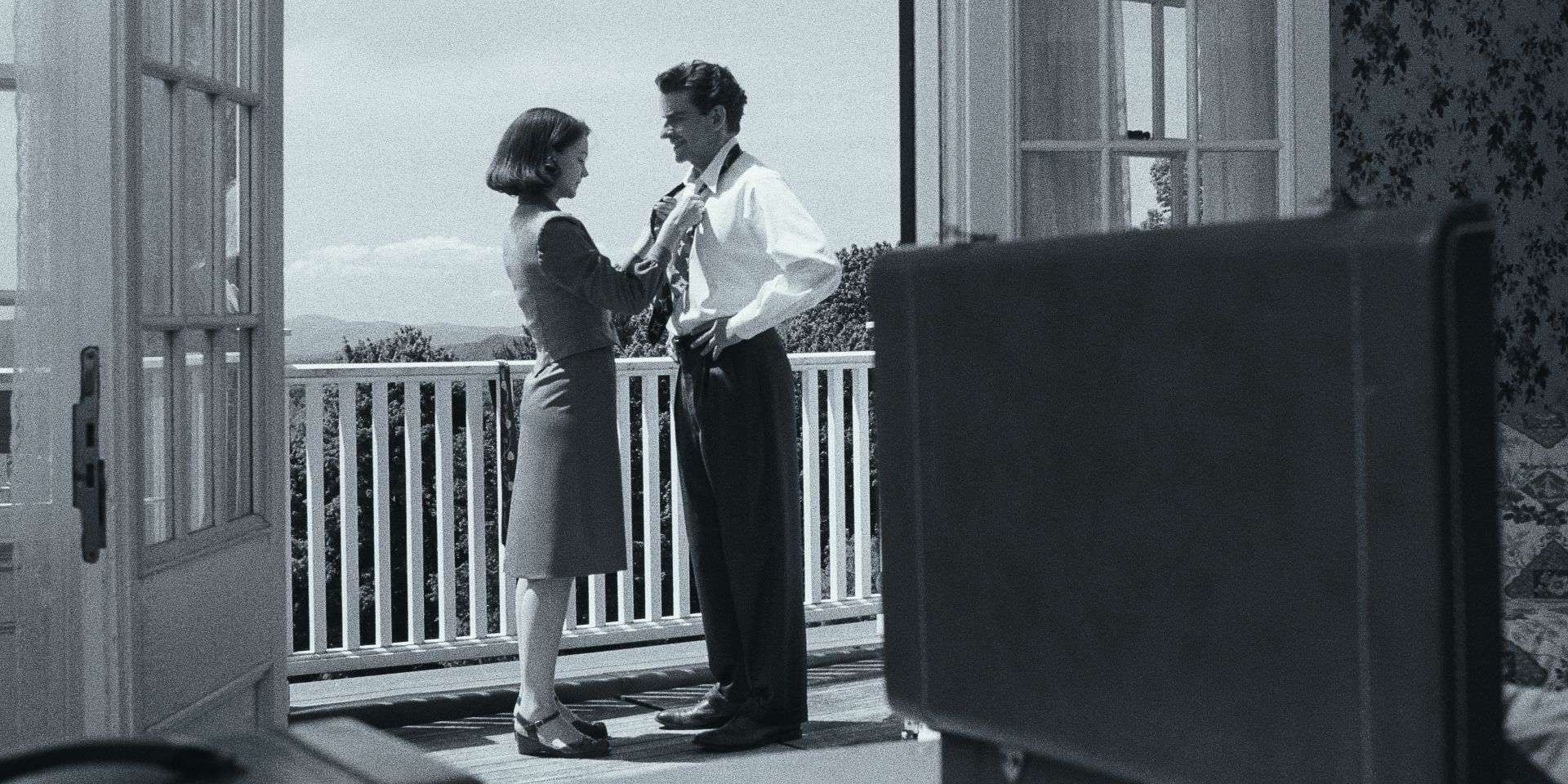 Carey Mulligan tying Bradley Cooper's tie in a black-and-white shot from Maestro