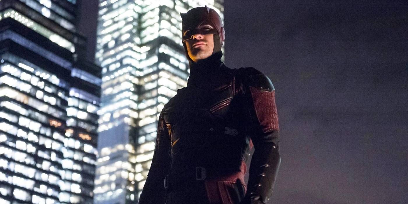 Charlie Cox as Daredevil from the Netflix series, at night against a lit up city backdrop.