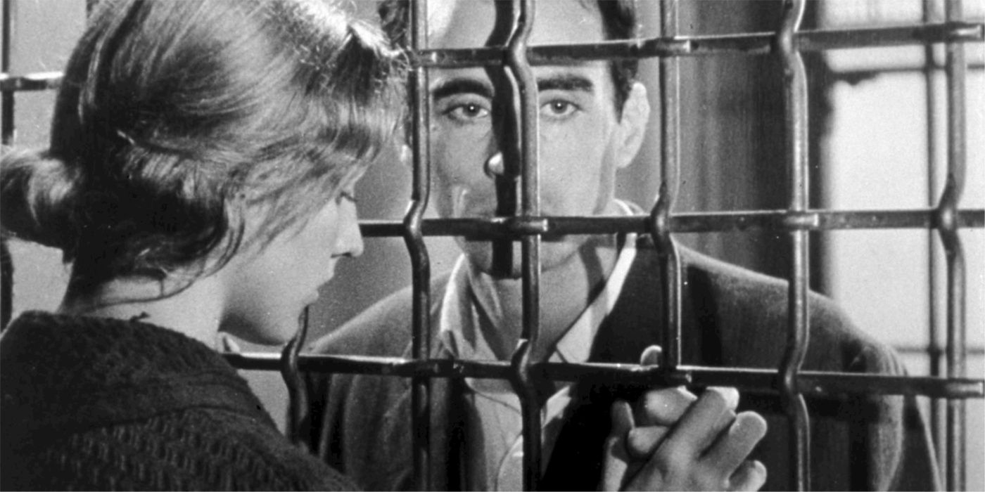 Michel stands behind bars in Pickpocket