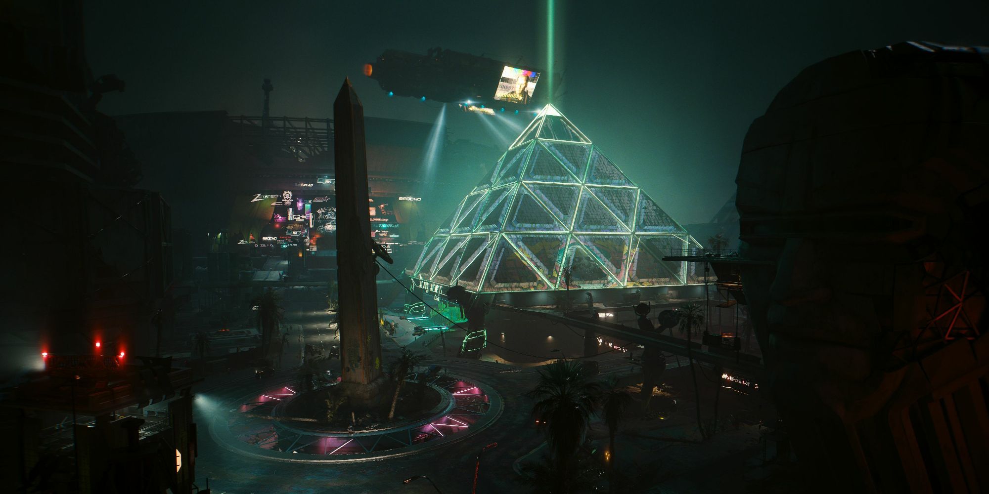 The lights of Dogtown at night, including the enormous, green-glowing pyramid, in a screenshot from Cyberpunk 2077.
