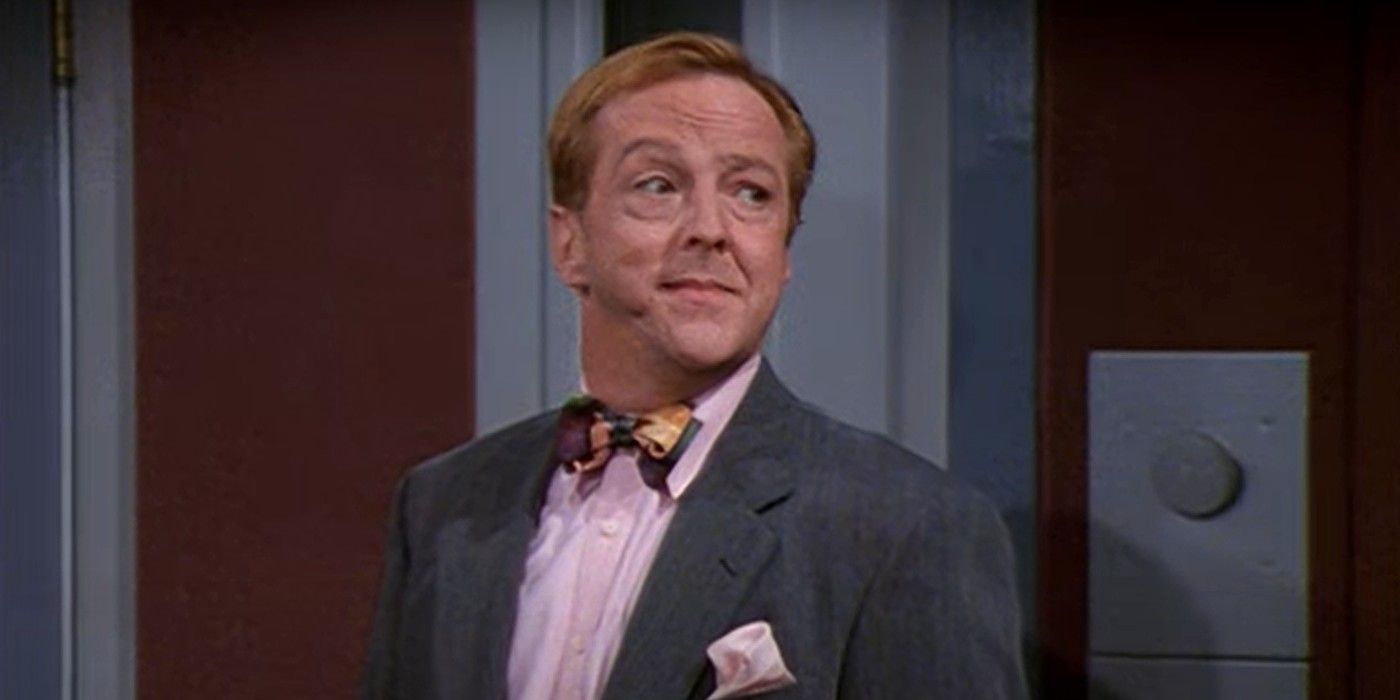 Edward Hibbert sebagai Gil dalam setelan jas dan dasi kupu-kupu melihat dari balik bahunya di Frasier