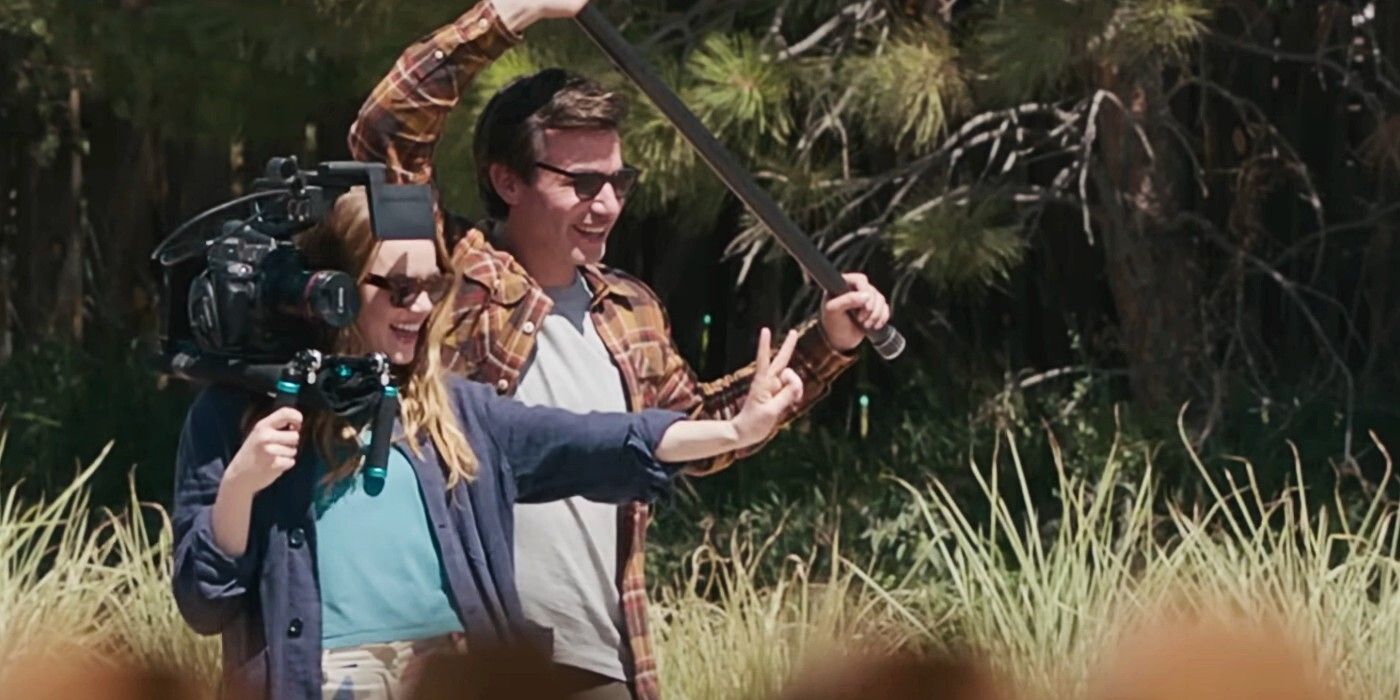 A screencap from The Curse of Emma Stone and Nathan Fielder. Both are wearing sunglasses and smiling. Nathan is holding a boom mic while Emma us holding a camera with one hand and throwing a peace sign with the other