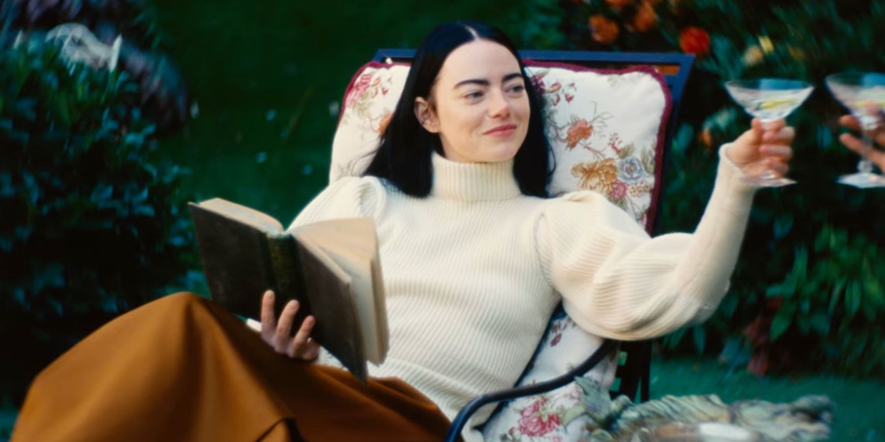 Emma Stone in Poor Things reading and toasting