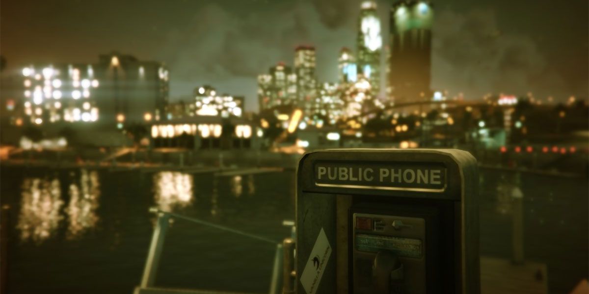 Public phone in the foreground with an out-of-focus city in the background.