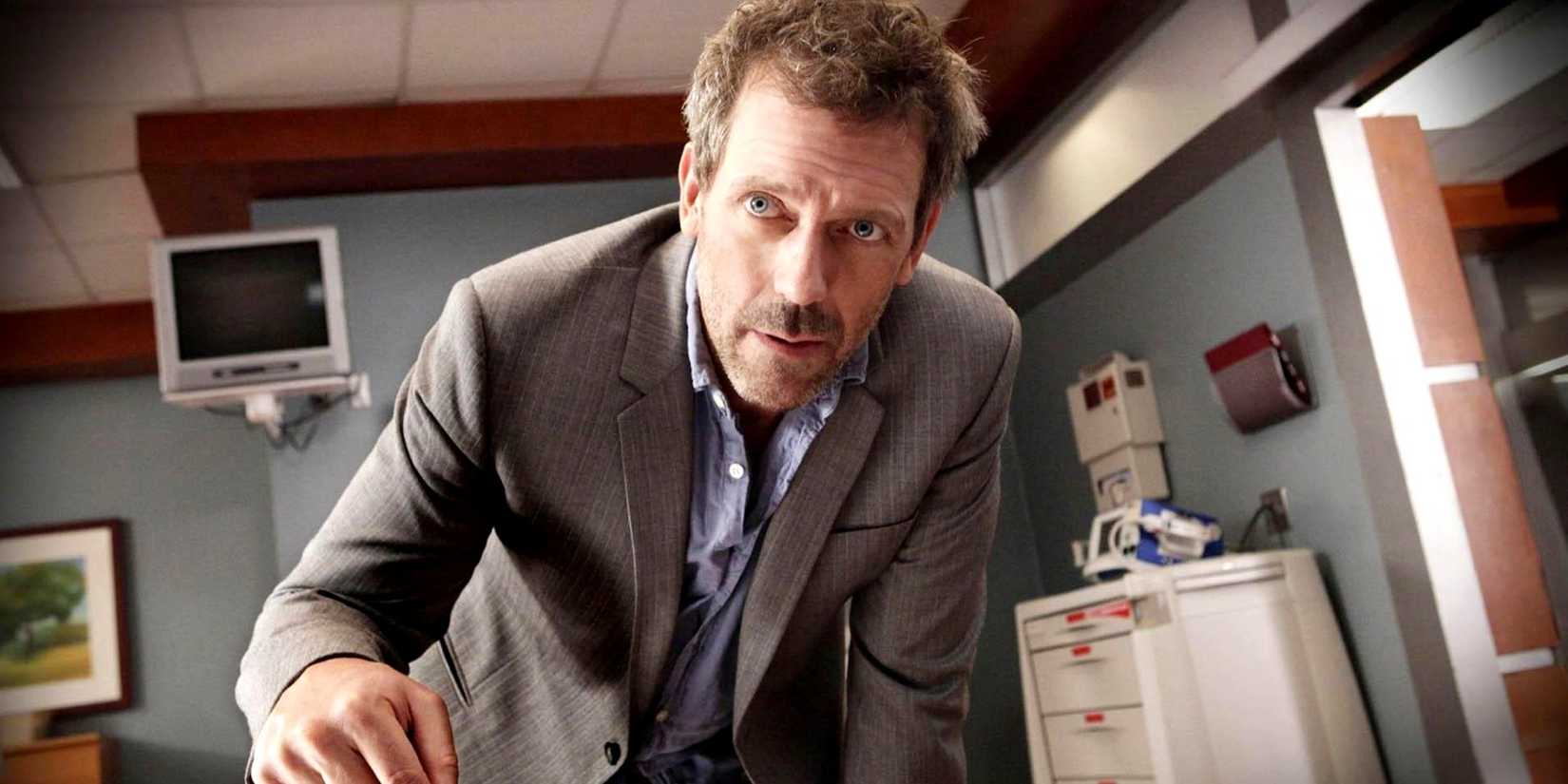 Hugh Laurie as House leaning over a table in House M.D.